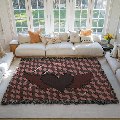 a woven blanket with a deep red heart with wings on a distorted checkered pattern on a living room floor