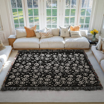 a woven blanket with a pattern of stitch mouthed emo ghouls and broken hearts on a dark background