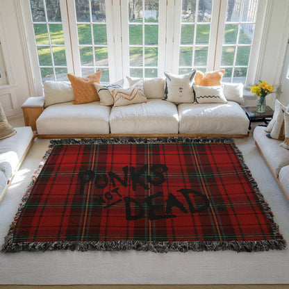 Red plaid woven blanket blanket with text 'Punks Not Dead' on a floor