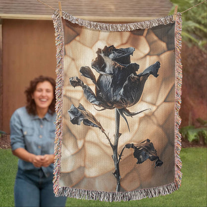a woven blanket with a black wilted rose and shattered beige background