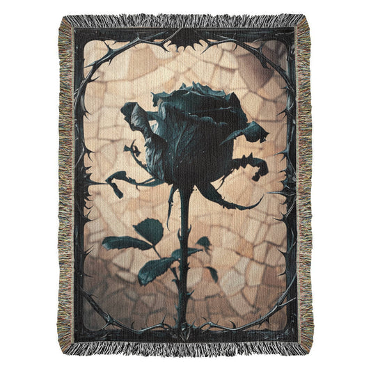 a woven blanket with a black wilted rose and shattered beige background, surrounded by a frame of thorns