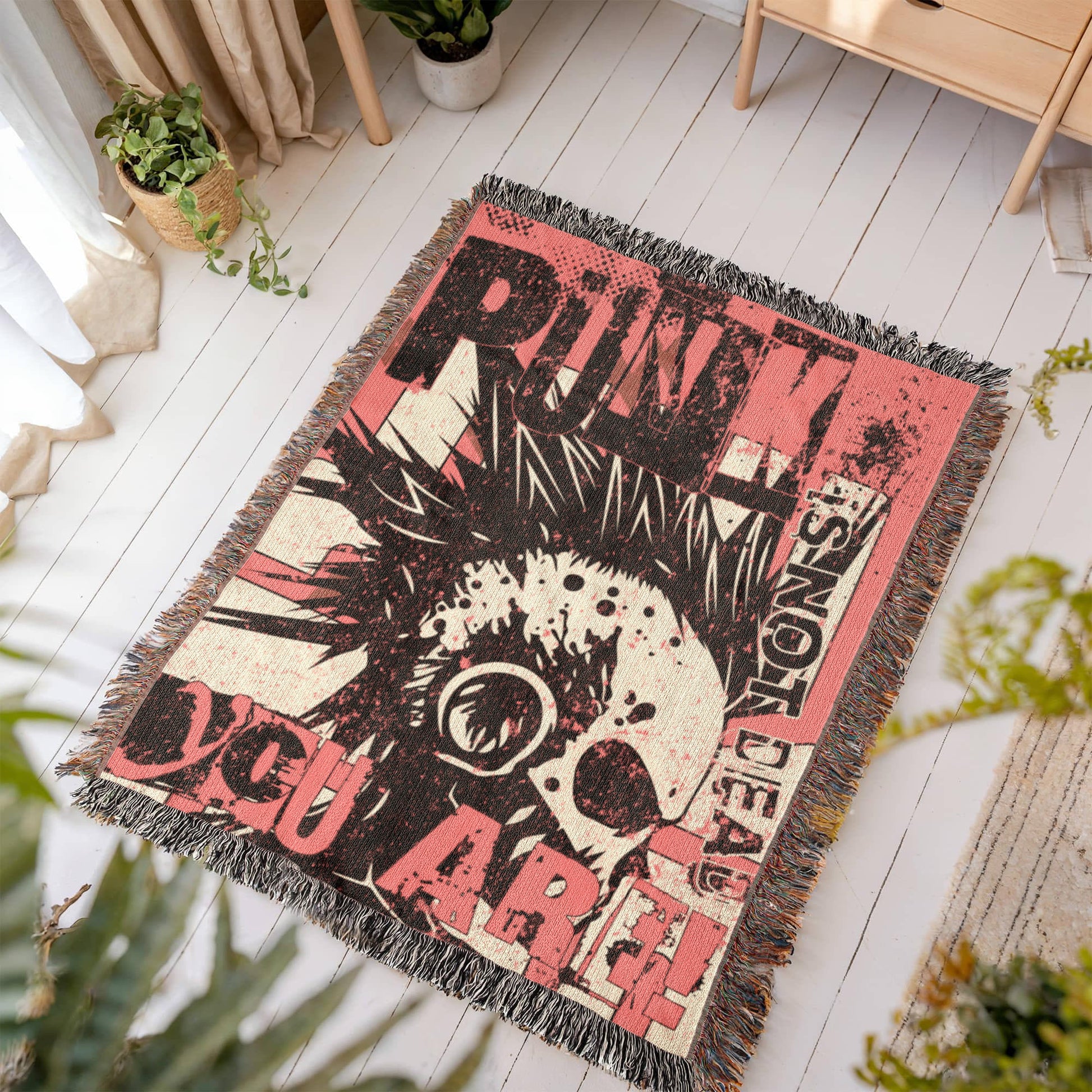 a woven blanket with a punk collage in pink and black, with text and a mohawk skull