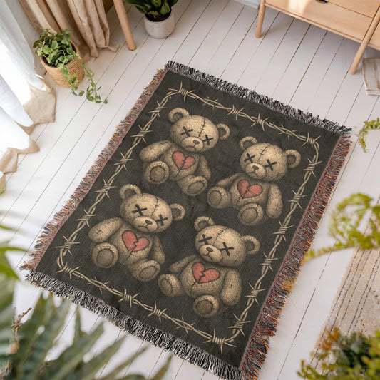 a woven blanket with x-eyed teddy bears on a dark background and surrounded by a frame of barbed wire