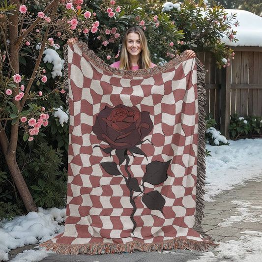 woman holding a woven blanket featuring distorted checkerboard patterns and a deep red soulful rose