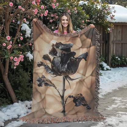 a woven blanket with a black wilted rose and shattered beige background