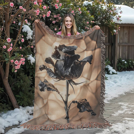 a woven blanket with a black wilted rose and shattered beige background