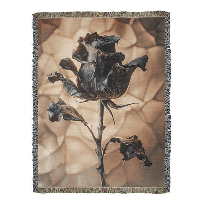 a woven blanket with a black wilted rose and shattered beige background