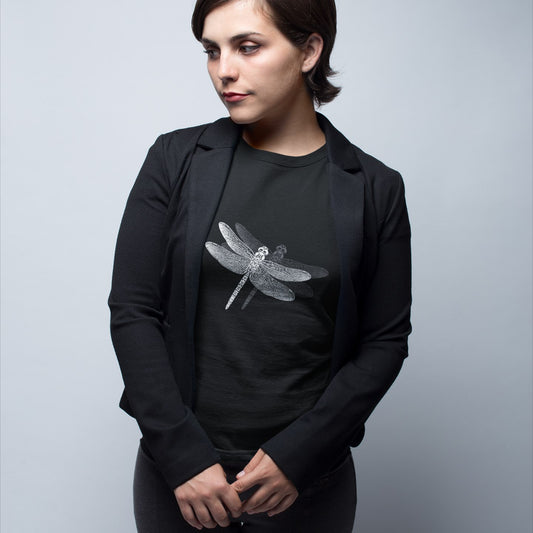 Woman wearing a blazer and a black t-shirt with a delicate dragonfly design