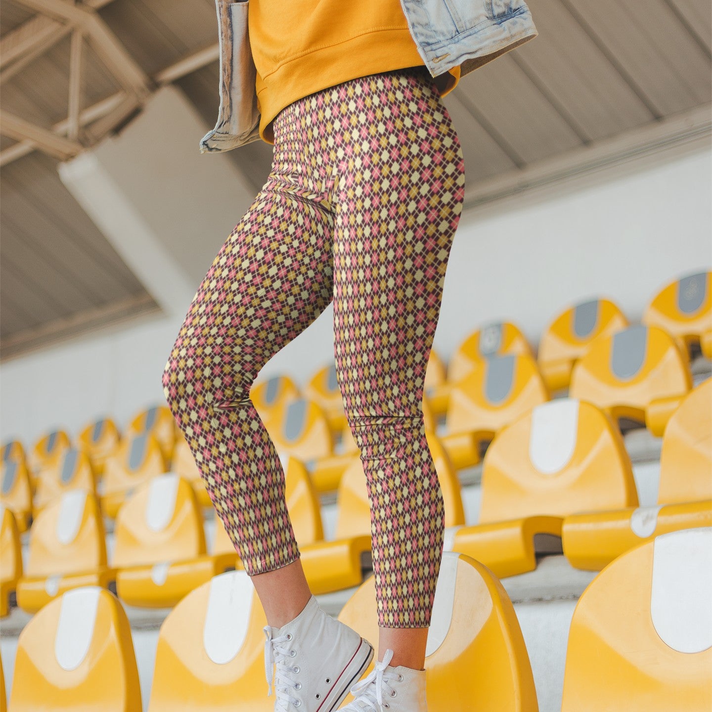 Person wearing colorful burgundy diamond patterned leggings and a yellow jacket in an indoor setting with yellow chairs.