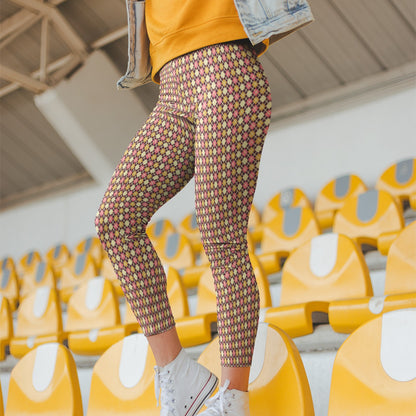 Person wearing colorful burgundy diamond patterned leggings and a yellow jacket in an indoor setting with yellow chairs.
