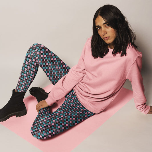 Woman wearing a pink sweatshirt and diamond patterned leggings sitting on a pink mat.