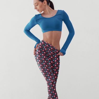 Woman wearing a blue long-sleeve crop top and diamond patterned leggings on a light gray background