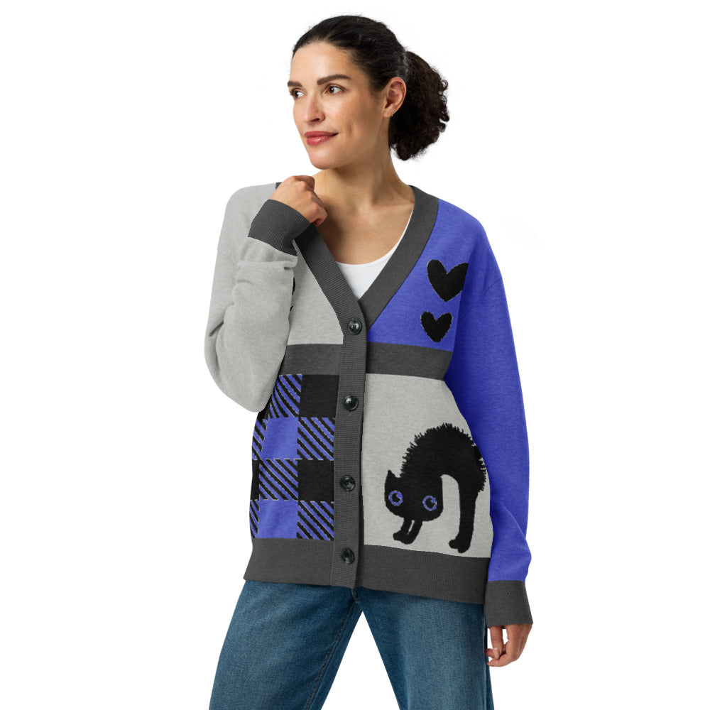 woman wearing a knitted cardigan with patchwork like design, plaid, hearts, spooky eyes and a cat