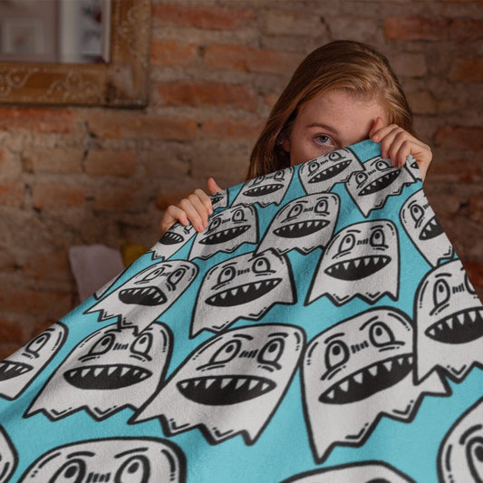 person holding a sky blue fleece sherpa blanket with grinning goblins