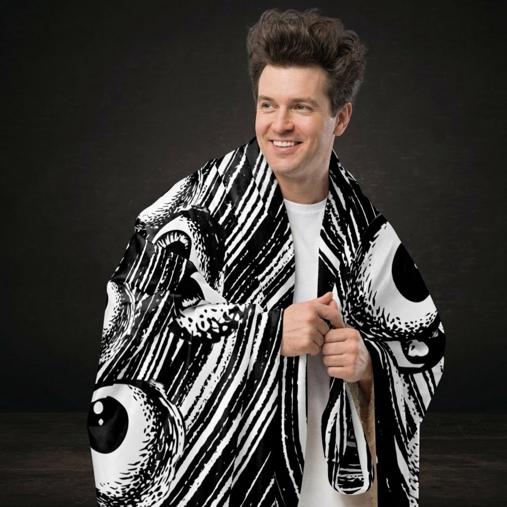 A large sherpa blanket with a black and white drawn vortex and eyeballs floating into it 