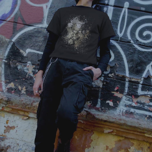 man wearing a black tee with subtle skull graphic surrounded and overlaid with paint splatter in camouflage colors