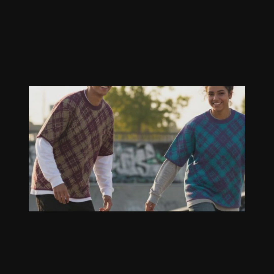 Two skaters wearing knitted tees with broken plaid pattern in cool street colors, over long sleeves