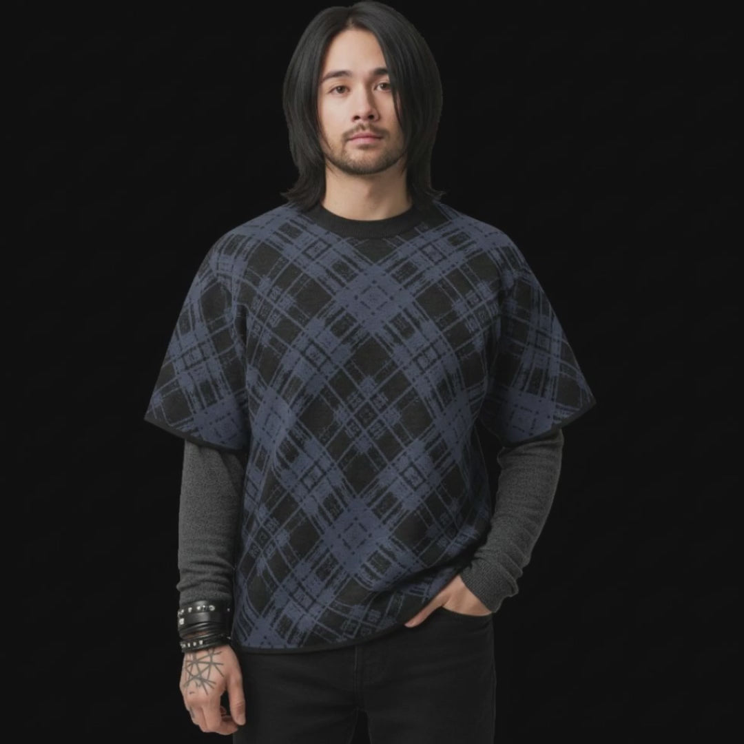 En emo style man wearing a knitted tee with a dark broken plaid pattern, layered over a long sleeve