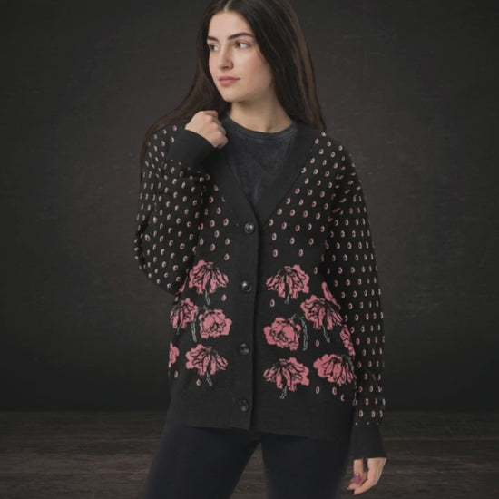 A woman wearing an emotional black knit cardigan with pink crying flowers and teardrops