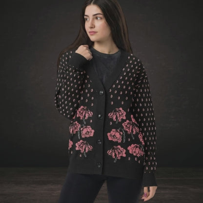 A woman wearing an emotional black knit cardigan with pink crying flowers and teardrops