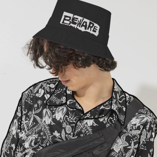 man wearing an old school black bucket hat with embroidered text "beware"