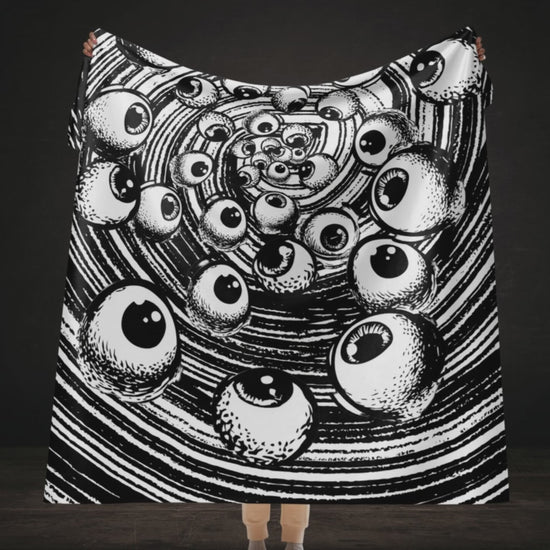 A large sherpa blanket with a black and white drawn vortex and eyeballs floating into it 