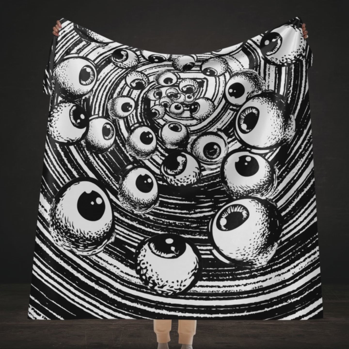 A large sherpa blanket with a black and white drawn vortex and eyeballs floating into it 