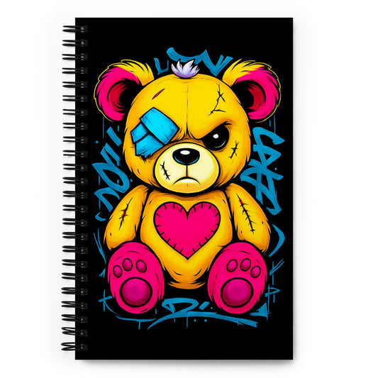 a spiral bound notebook with an angry looking stitched teddy bear on the cover