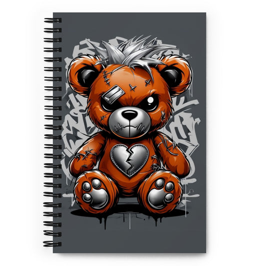 a spiral bound notebook with an angry looking stitched teddy bear on the cover