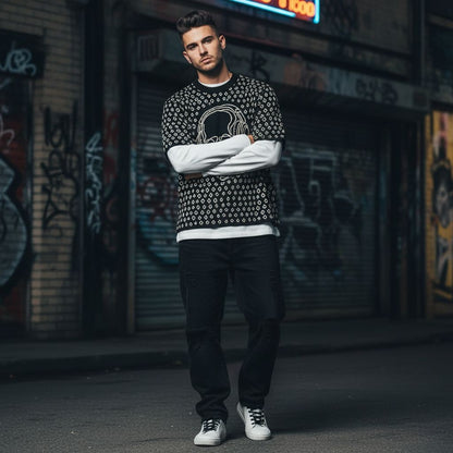 Man wearing a black short sleeve knit featuring a line art skull with headphones and hand drawn diamonds, layered over a long sleeved tee