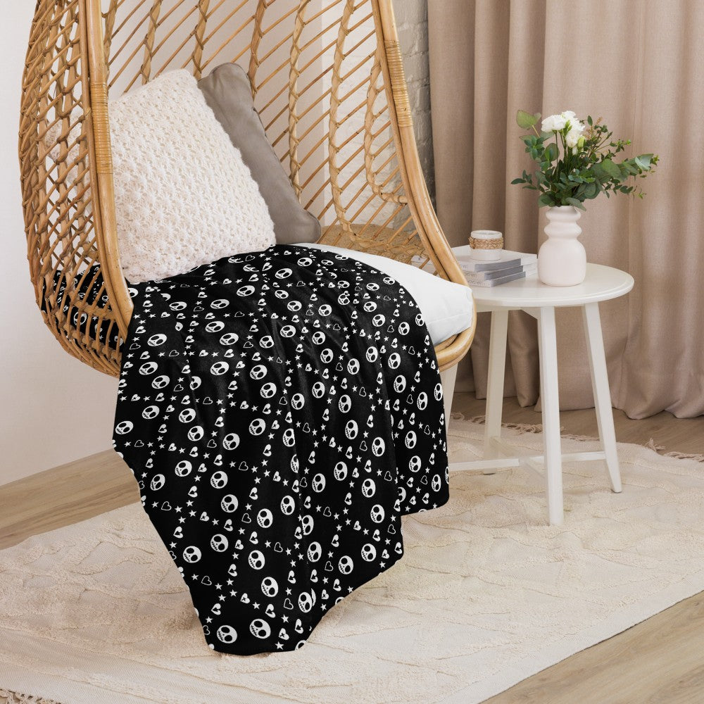 Black sherpa blanket with repeating white skull/ghoul, heart, and star geometric pattern, alt and emo aesthetic throw