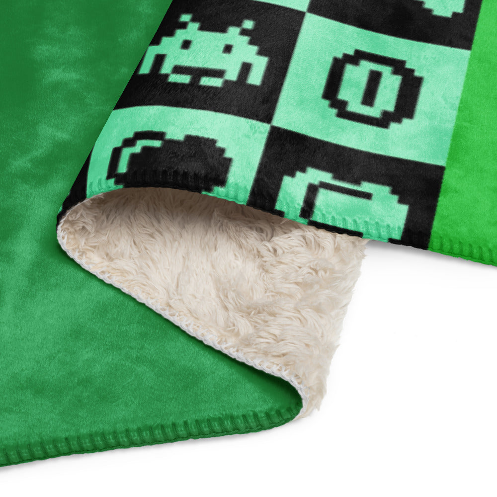 a fleece sherpa blanket with squares and very other square filled with retro pixaleted gaming symbols