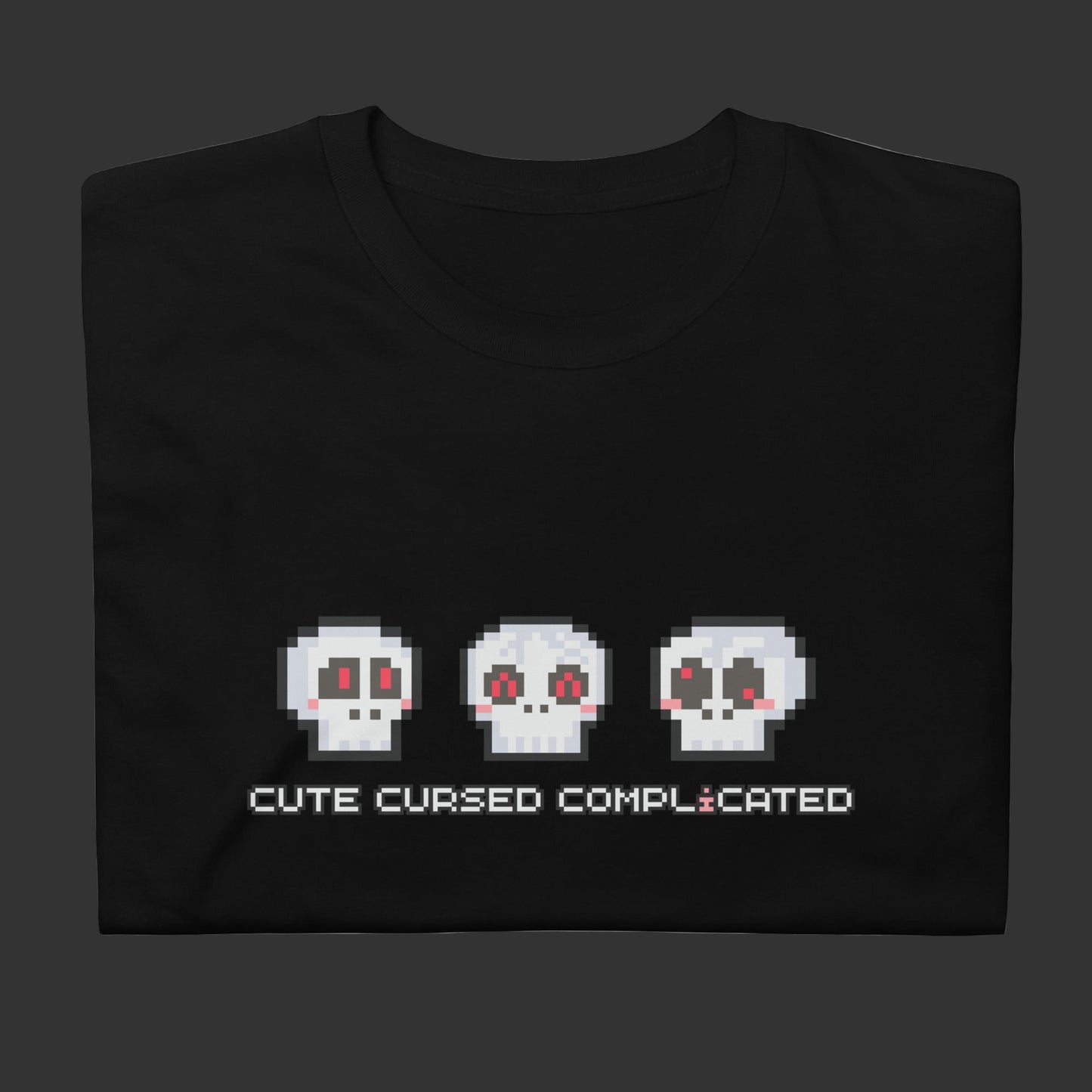 A t-shirt with pixel art skulls and text "cute cursed complicated"