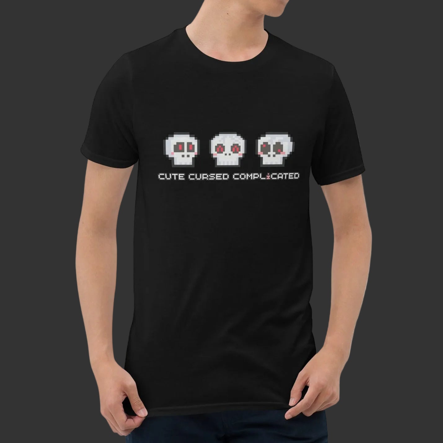 Person wearing a t-shirt with pixel art skulls and text "cute cursed complicated"
