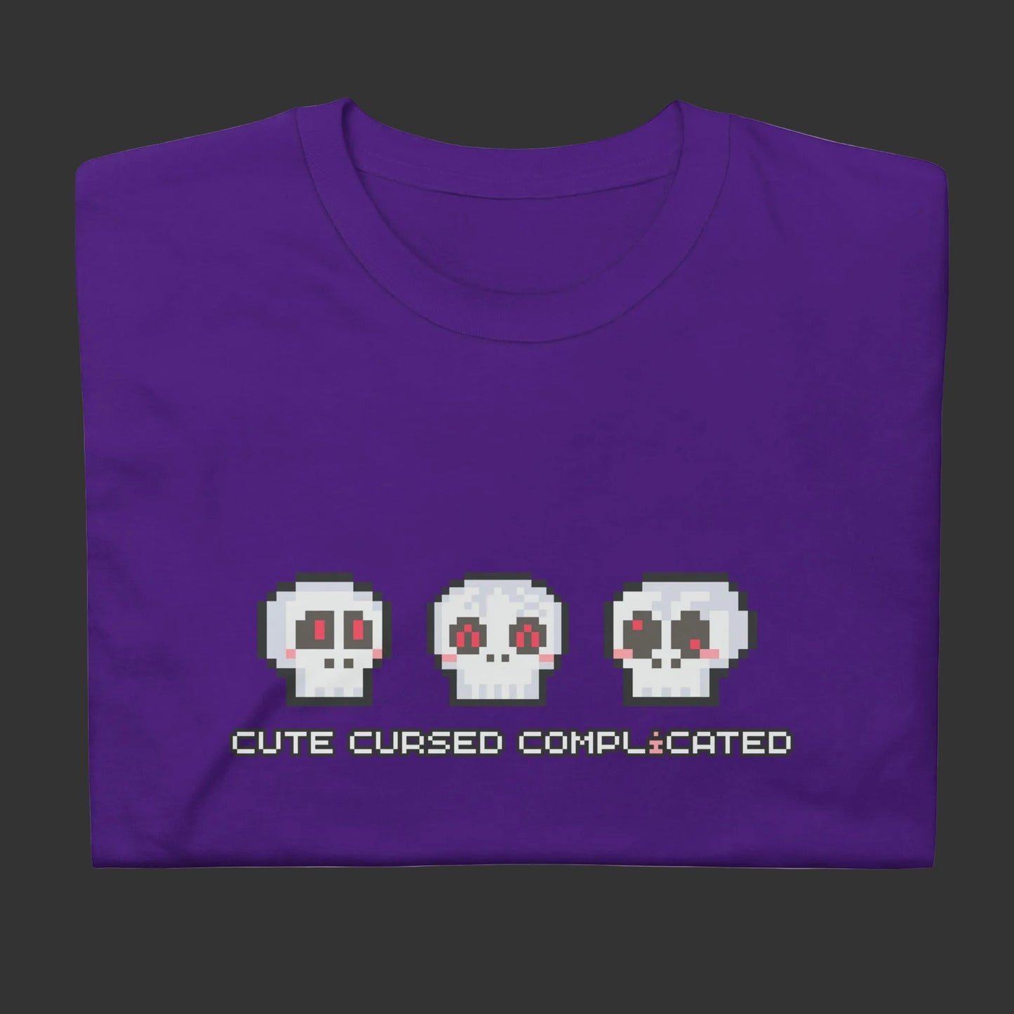 A purple t-shirt with pixel art skulls and text "cute cursed complicated"