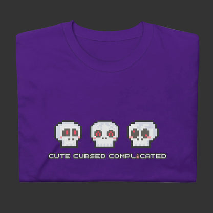 A purple t-shirt with pixel art skulls and text "cute cursed complicated"
