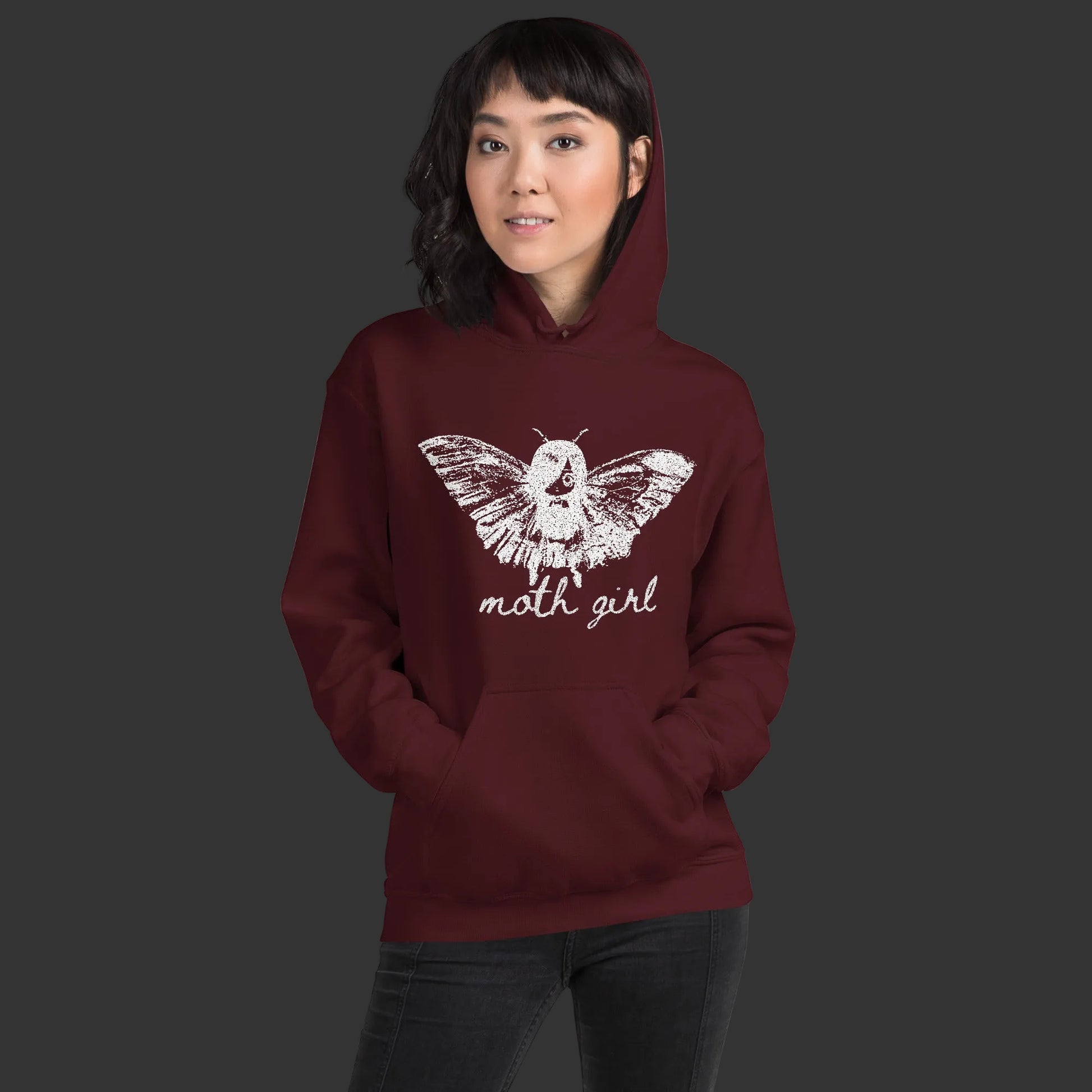 Person wearing a hoodie with a distressed pointillism design of an emo girl with moth wings and the text "moth girl"