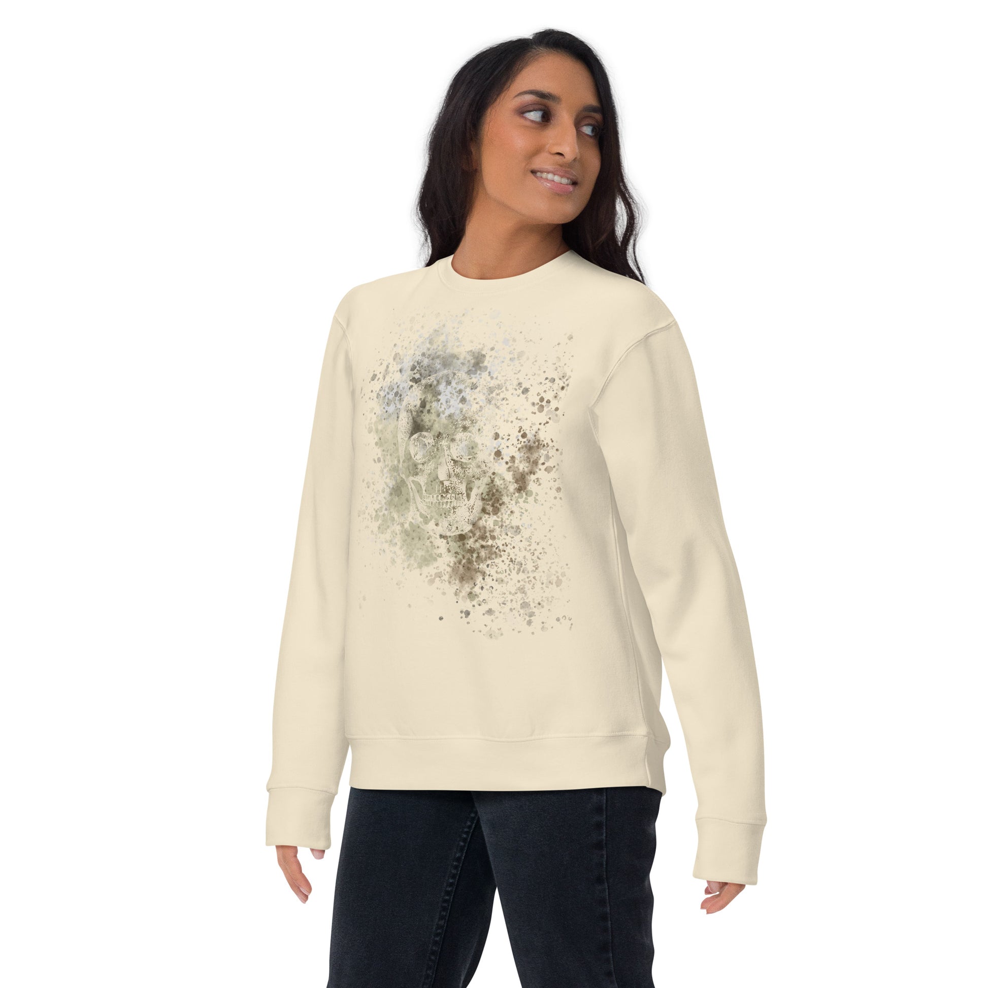 woman wearing a sweatshirt with subtle skull graphic surrounded and overlaid with paint splatter in camouflage colors on bone white