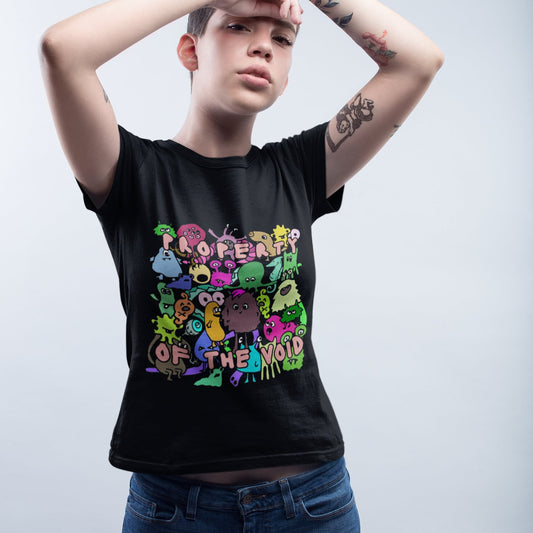 Person wearing a black t-shirt with colorful graphic design, with emo and scene kid monsters and text property of the void