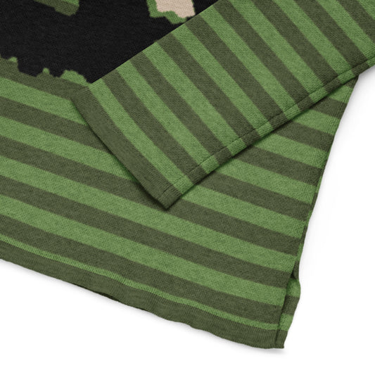 detail of green striped sweater with a large x-eyed skull design