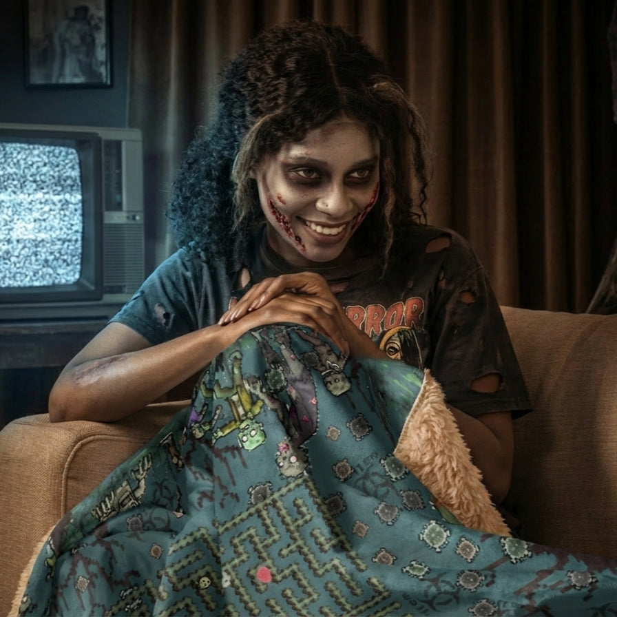 Zombie fan woman curled up in a sofa with a large pixel art zombie maze sherpa blanket